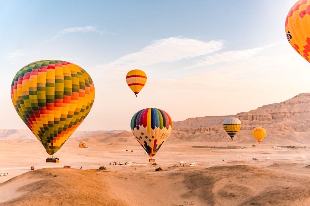 Colorful hot air balloons floating over Luxor desert at sunrise.