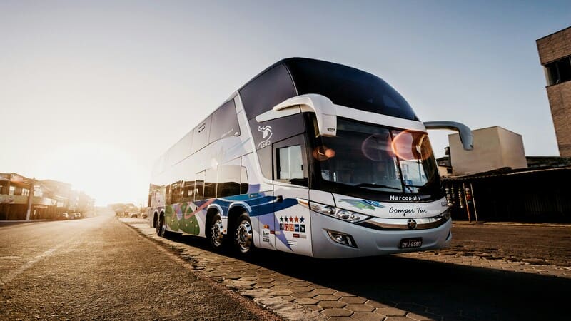 A sleek, modern double-decker tour bus parked on a sunlit street, ready for an adventurous journey