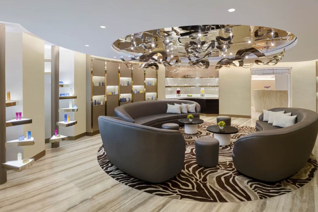 A modern spa lounge area with curved sofas, stylish decor, and a reflective ceiling creating a luxurious atmosphere