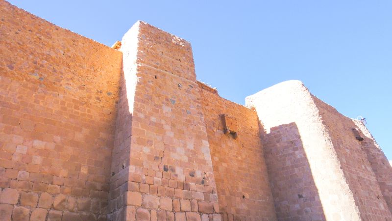 Exterior walls of Saint Catherine's Monastery in bright sunlight showcasing the fortified ancient structure.