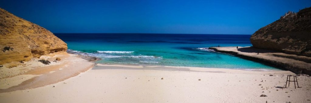 Tranquil beach scene in Dahab with clear blue waters and white sand.