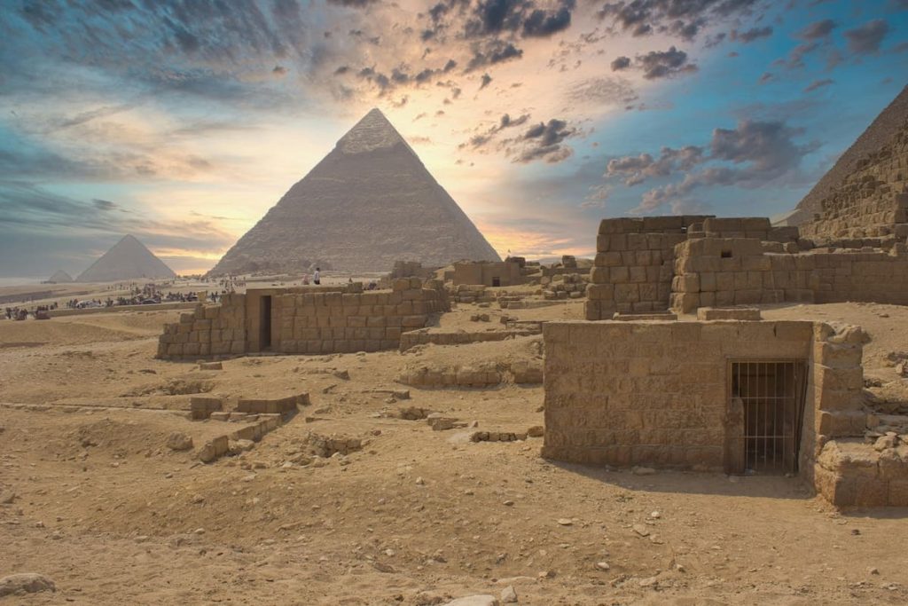 Ancient pyramids and stone ruins under a cloudy sky at the Giza Plateau in Egypt.