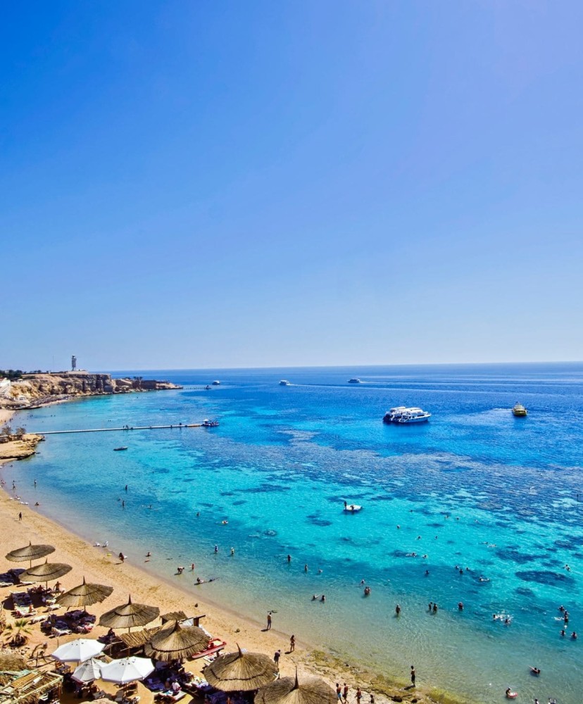 A stunning beach in Sharm El Sheikh with clear blue waters and umbrellas on the sandy shore.