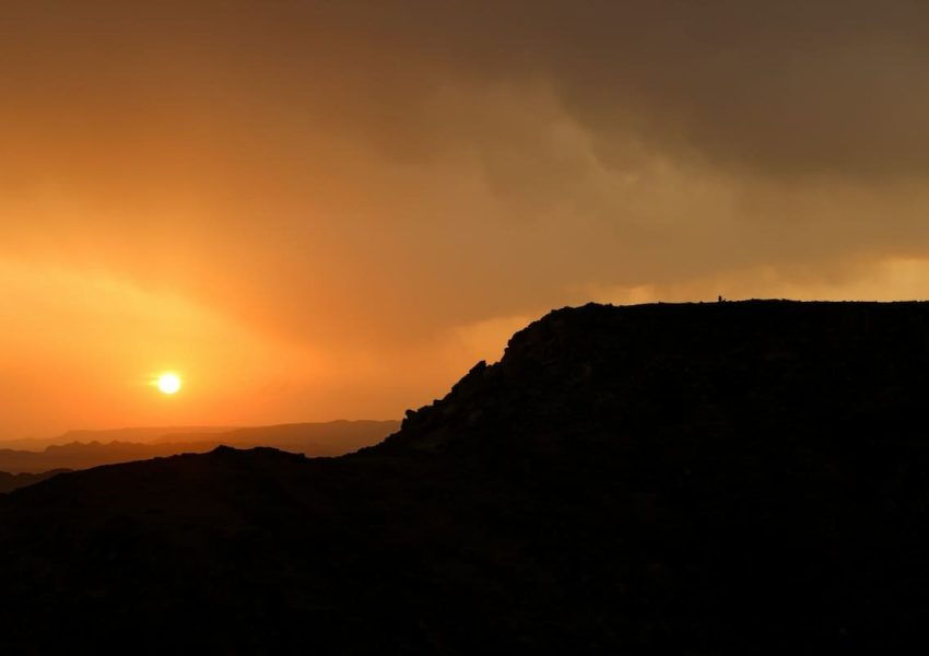 Sunset over a rugged mountain ridge with a glowing orange sky