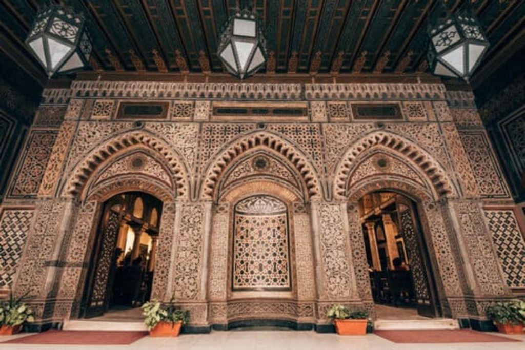 An intricately decorated arched entrance of a historical building with detailed carvings and mosaic tilework.