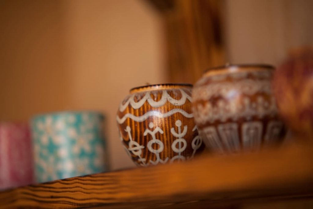 Close-up of three handcrafted pottery pieces with intricate white patterns on a wooden shelf