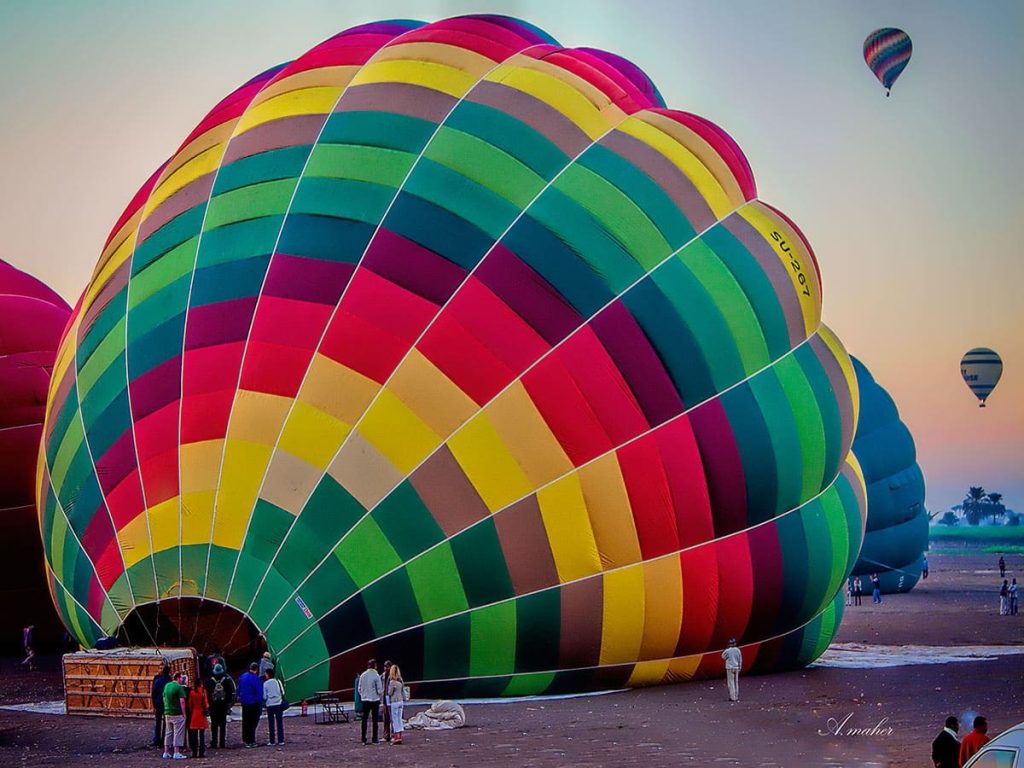 Colorful hot air balloons soaring over Luxor's ancient landscape at sunrise