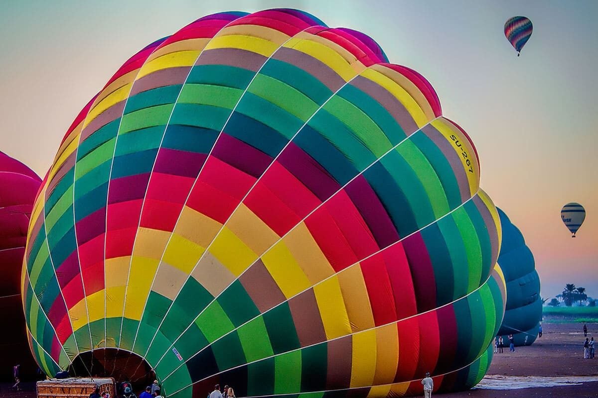 Colorful hot air balloons soaring over Luxor's ancient landscape at sunrise