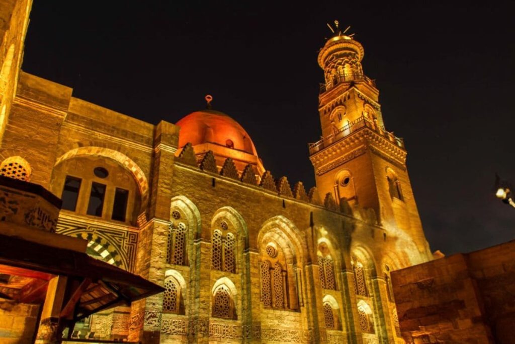 Night view of Cairo's historic mosque and surrounding buildings illuminated by city lights