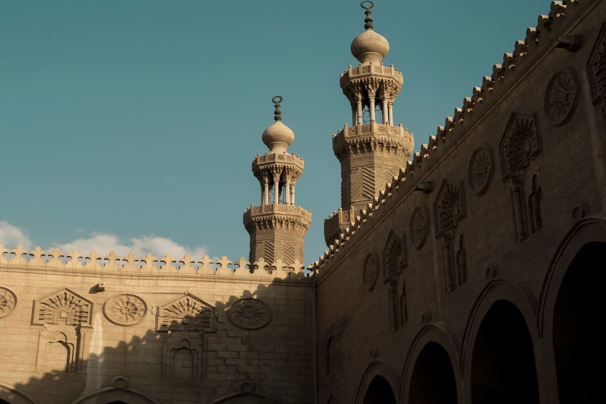 The minarets of Al-Azhar Mosque, standing tall against a clear blue sky, showcasing Islamic architectural beauty