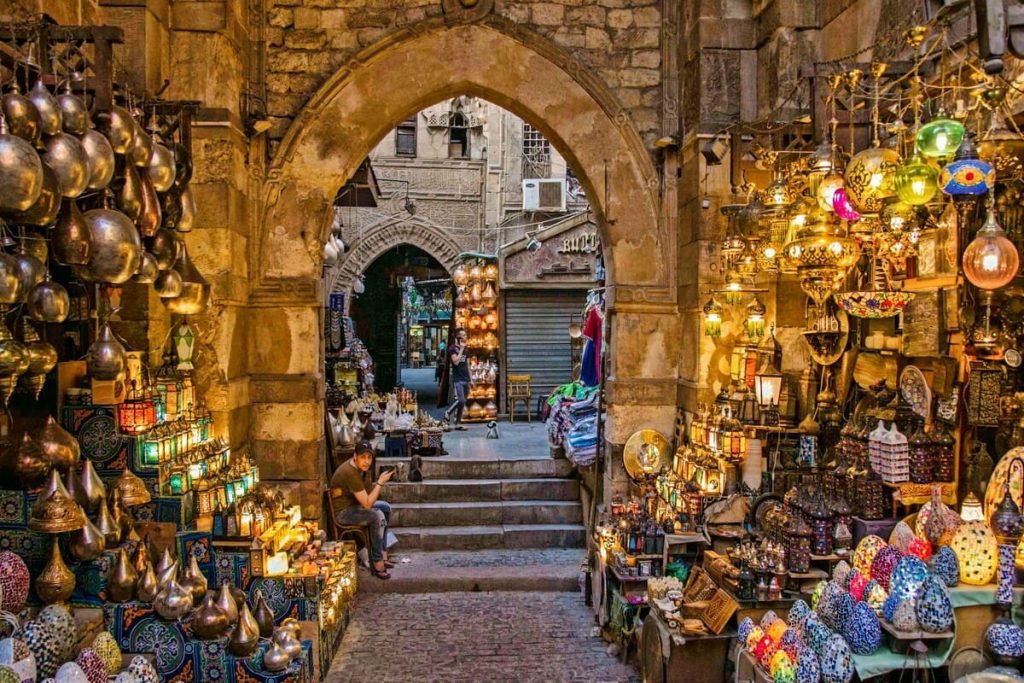 A vibrant and bustling market in Cairo with colorful stalls, various goods, and many people shopping