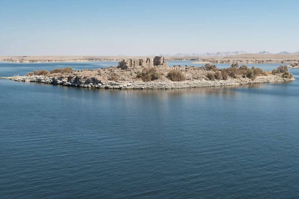 An aerial view of Qasr Qarun, a historic ruin on a small island in Lake Qarun, Egypt, surrounded by the expansive blue waters