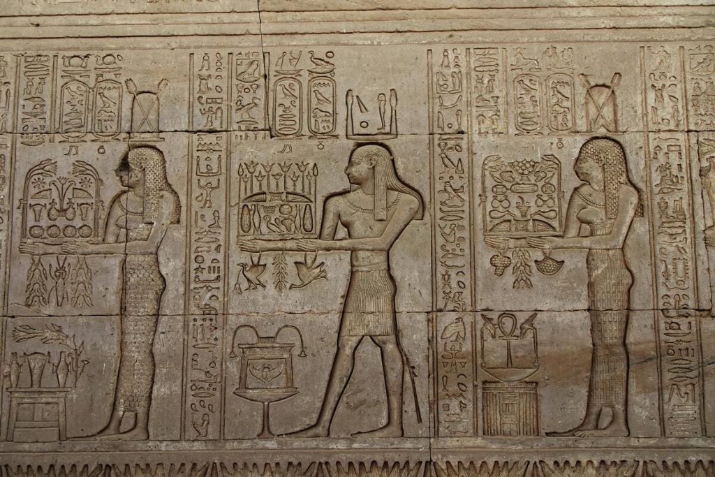 ntricate hieroglyphic carvings on an ancient Egyptian temple wall, depicting scenes and symbols from ancient Egyptian culture