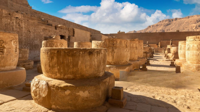 Ruins of Karnak Temple with large stone basins under a bright sky.