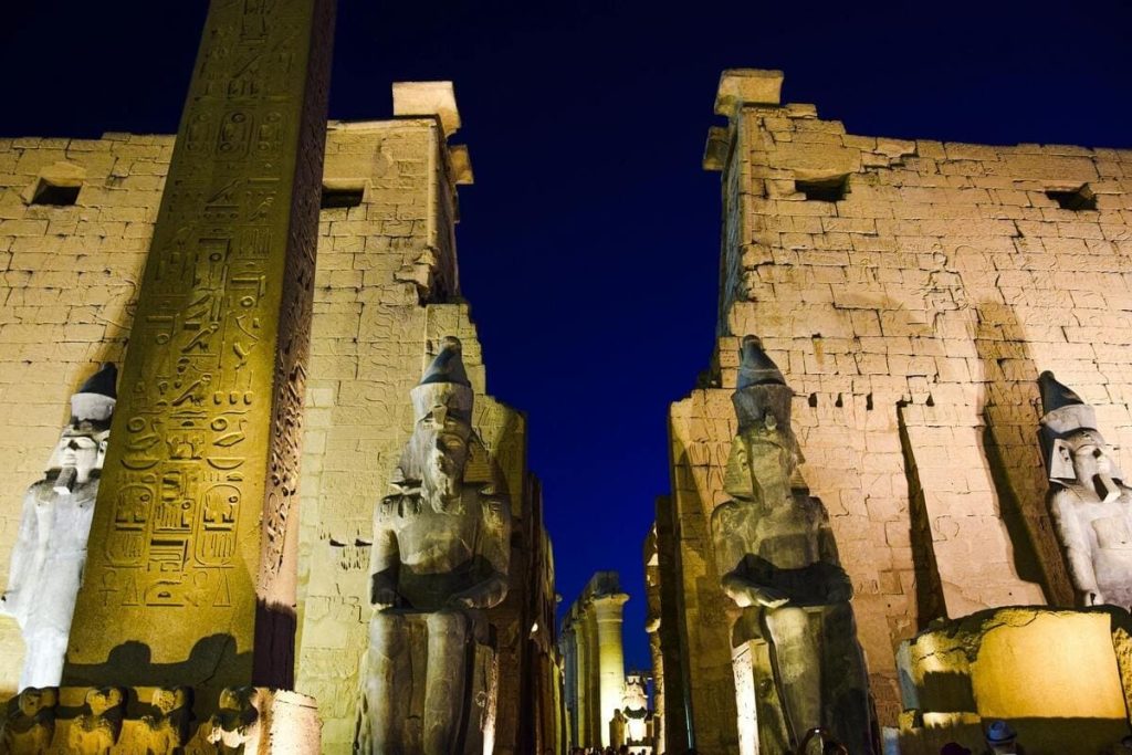 Luxor Temple illuminated at night, featuring statues and an obelisk