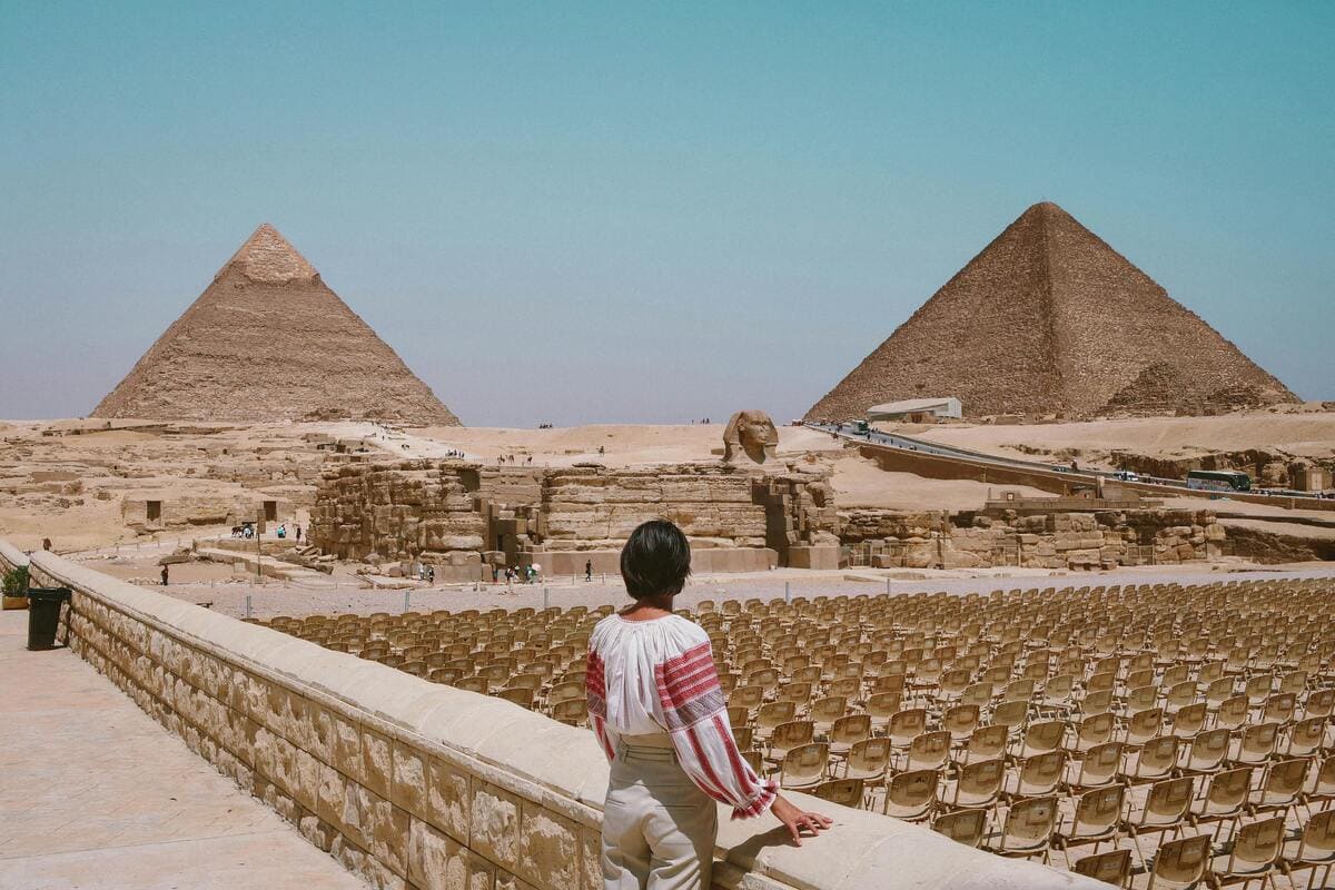 The Pyramids of Giza under a clear sky with distant tourists