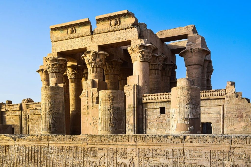 The twin temples of Kom Ombo, with intricate carvings and symmetrical columns, set against a backdrop of clear blue sky