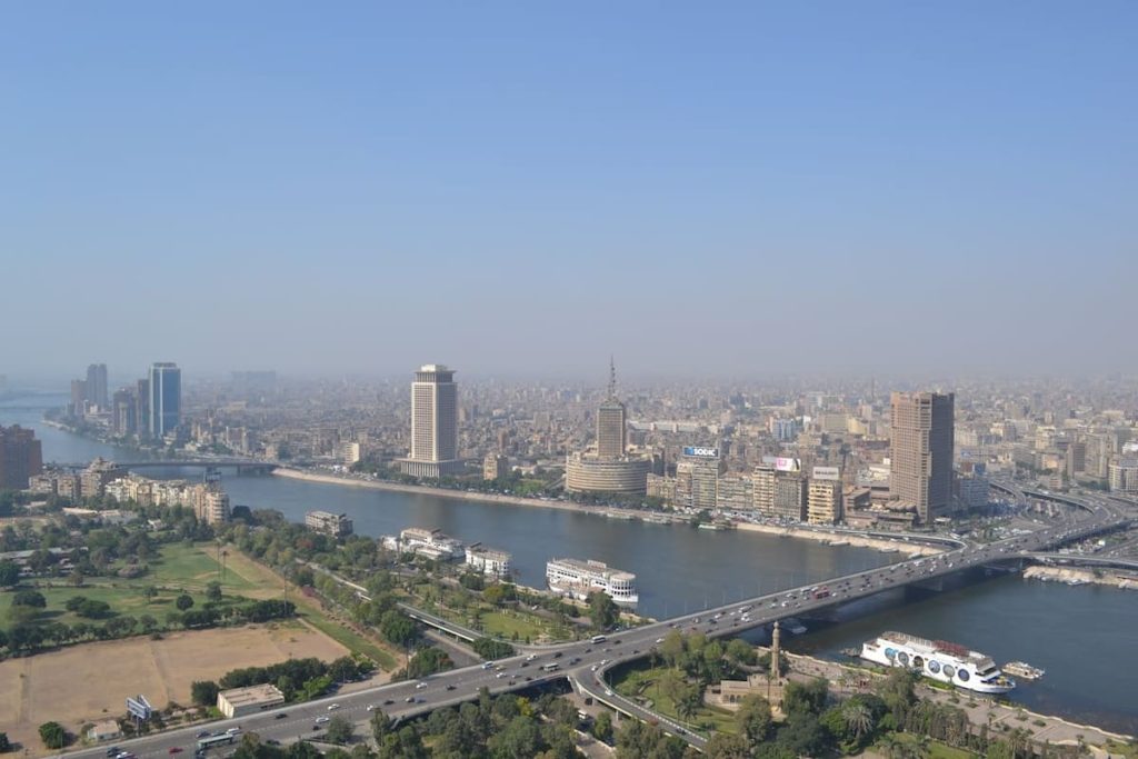 A vibrant downtown scene in Cairo with modern buildings, bustling streets, and a mix of traditional and contemporary architecture under a clear blue sky