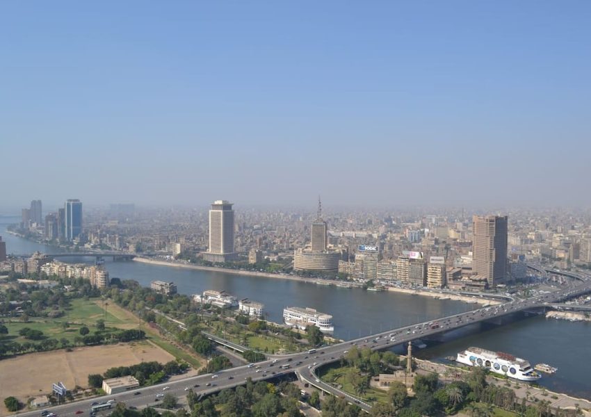 A vibrant downtown scene in Cairo with modern buildings, bustling streets, and a mix of traditional and contemporary architecture under a clear blue sky