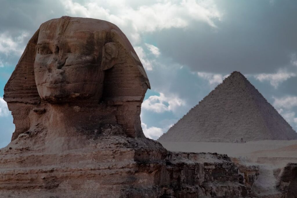 Iconic Egyptian pyramids rising majestically from the golden sands of the Giza Plateau under a clear, sunny sky in August