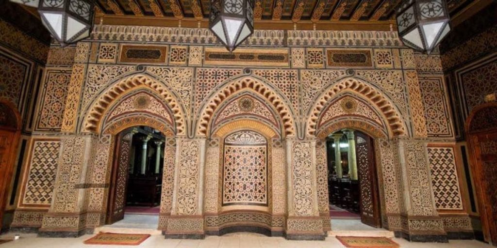 A detailed view of intricately carved wooden archways and patterned walls inside an ornate building in Old Cairo, showcasing traditional Islamic architecture.