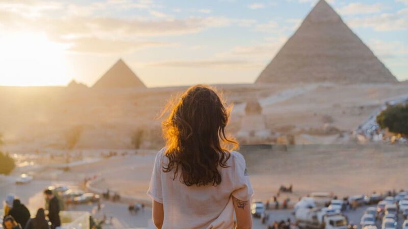 The Pyramids of Giza under a clear blue sky with desert sands in the foreground.