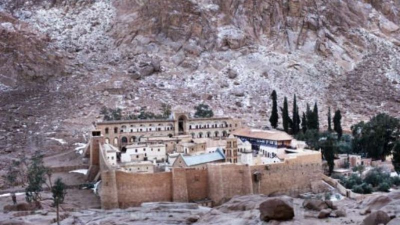 St. Catherine's Monastery at the base of Mount Sinai, Egypt, featuring ancient stone walls, rugged mountains, and a serene desert backdrop