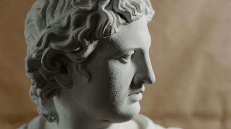 Marble bust of a Greco-Roman figure with intricate detailing on the hair and facial features