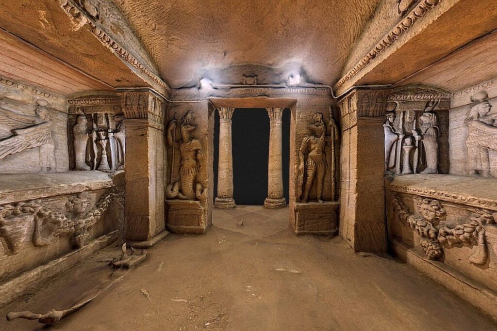 An interior view of the Catacombs of Kom El Shoqafa, showcasing ancient carvings, columns, and intricate architectural details