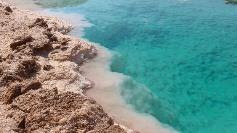 Rugged salt formations meeting the turquoise waters of a salt lake