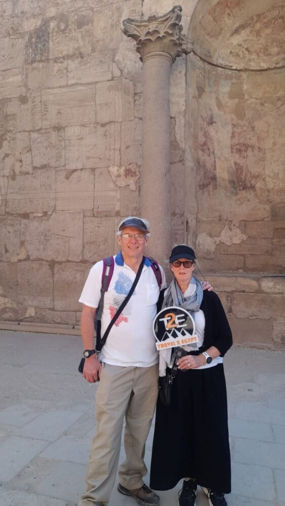 A couple posing at an ancient Egyptian temple with stone carvings and a tall column in the background