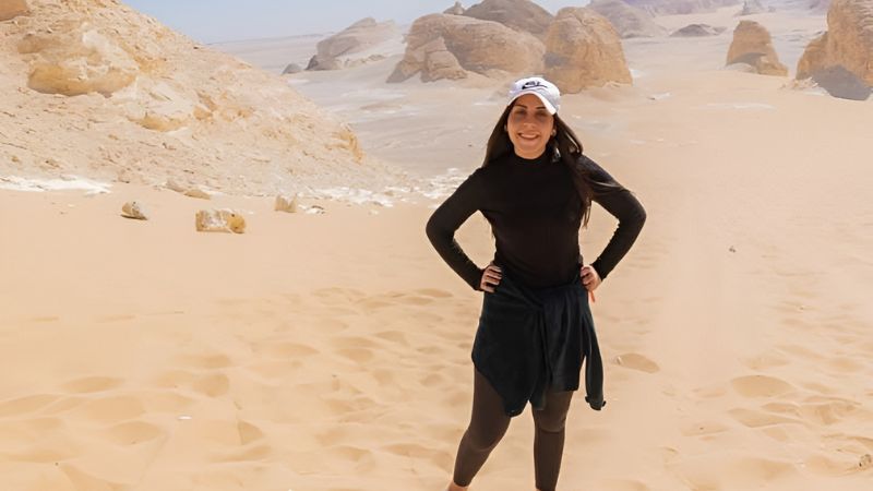 A woman standing confidently in a vast desert with rock formations in the background