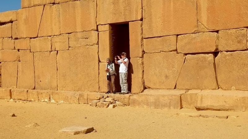 A magnificent ancient desert temple in Egypt, surrounded by golden sands and illuminated by soft sunlight, showcasing intricate carvings and grand architecture