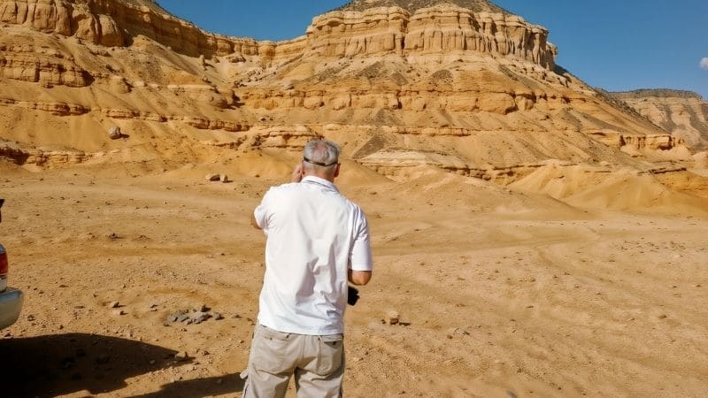 Majestic desert cliffs in Egypt, towering over a rugged landscape of golden sand and rocky terrain under a clear blue sky