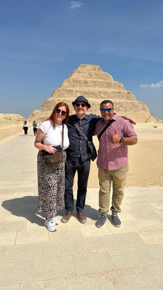 Tourists posing in front of the Step Pyramid of Saqqara under a clear sky