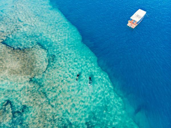 Crystal-clear waters with snorkelers and a small boat floating nearby in El Gouna