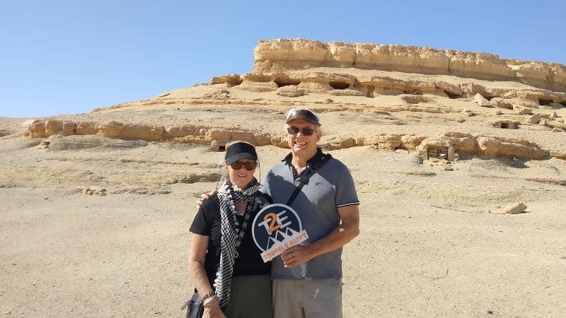 A stunning view of ancient desert caves in Egypt, surrounded by golden sands and rocky formations under a clear blue sky