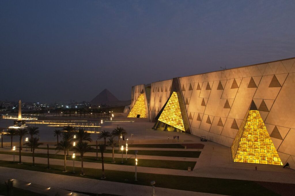 The Grand Egyptian Museum's sleek modern architecture with glass and geometric design elements, located near the Giza Pyramids