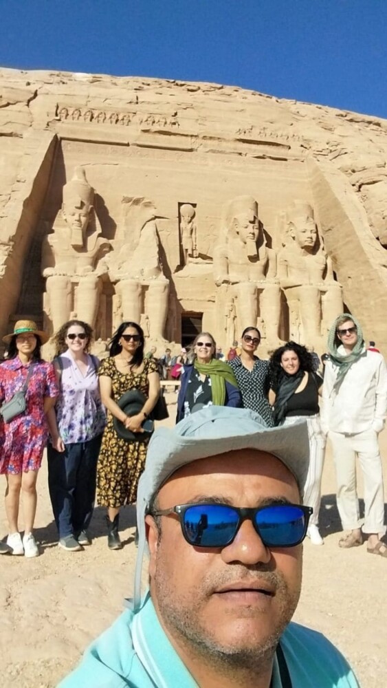 A group of tourists posing in front of the Abu Simbel Temple with massive statues of Pharaoh Ramses II