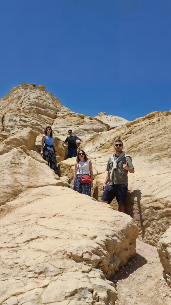 Tourists exploring sandstone rock formations under a clear blue sky in the Egyptian desert