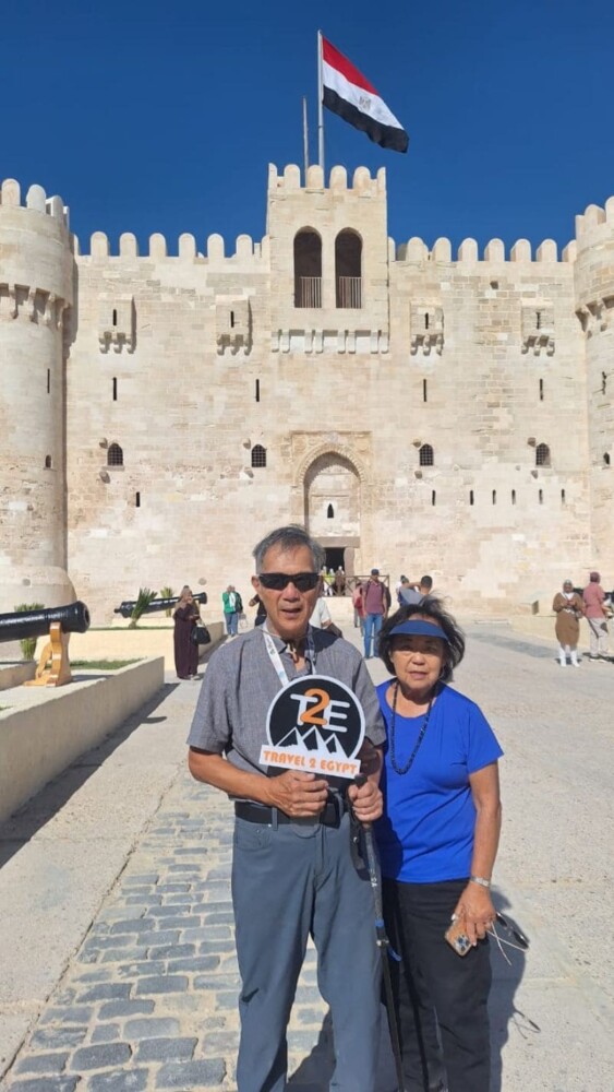 A couple posing in front of the historic Citadel of Qaitbay in Alexandria, Egypt