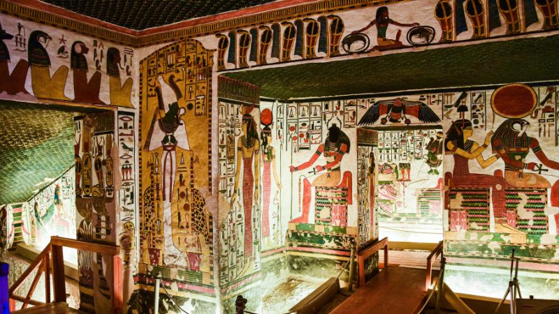 The vividly painted interior walls of an ancient Egyptian tomb in the Valley of the Kings, adorned with intricate hieroglyphs and deities