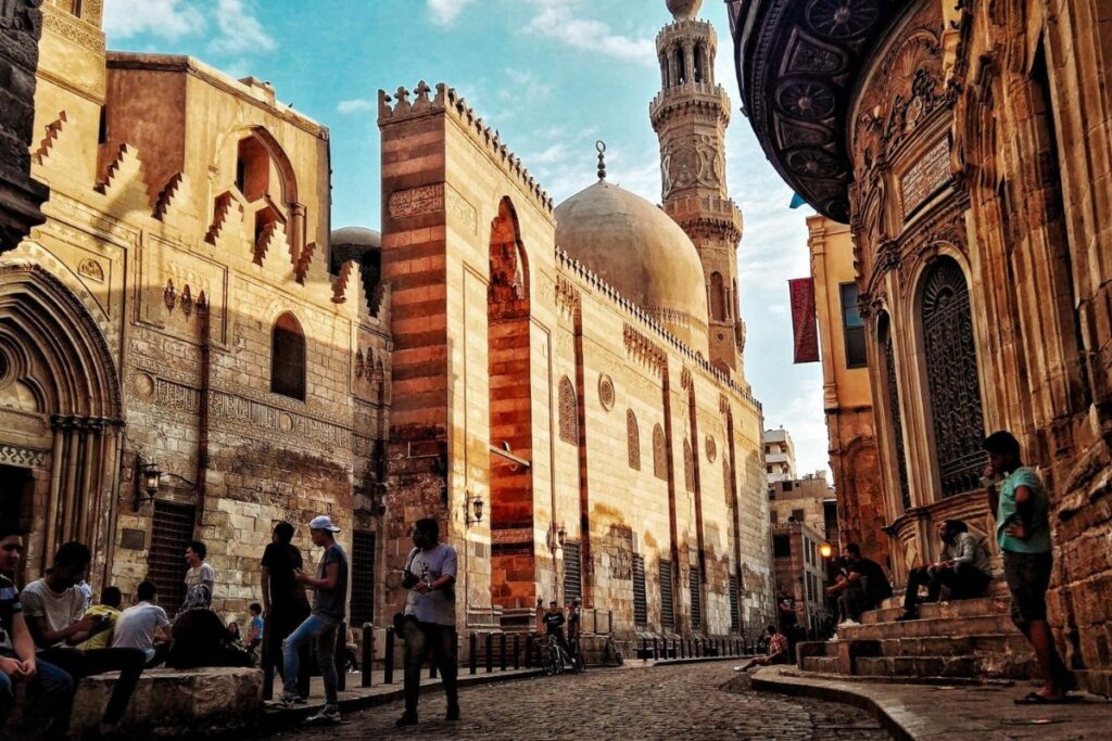 A panoramic view of Old Cairo, featuring historic mosques, traditional architecture, and vibrant local streets under a clear sky