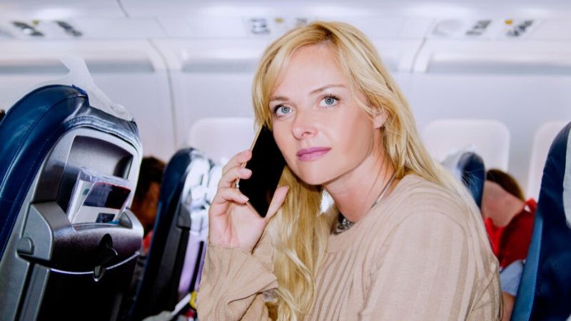 Woman talking on a mobile phone while seated on an airplane.