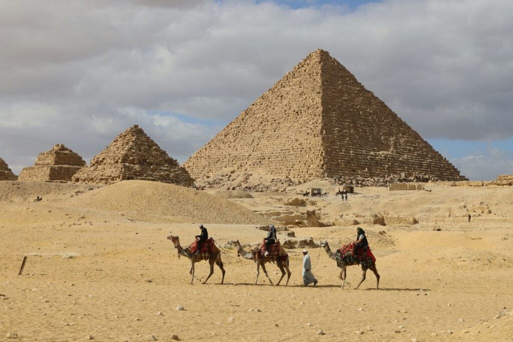 The majestic Pyramids of Giza under a bright blue sky, surrounded by desert sands