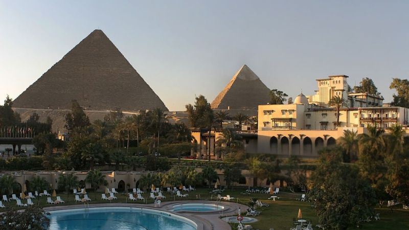 View of the Pyramids of Giza with a luxurious hotel and a pool in the foreground