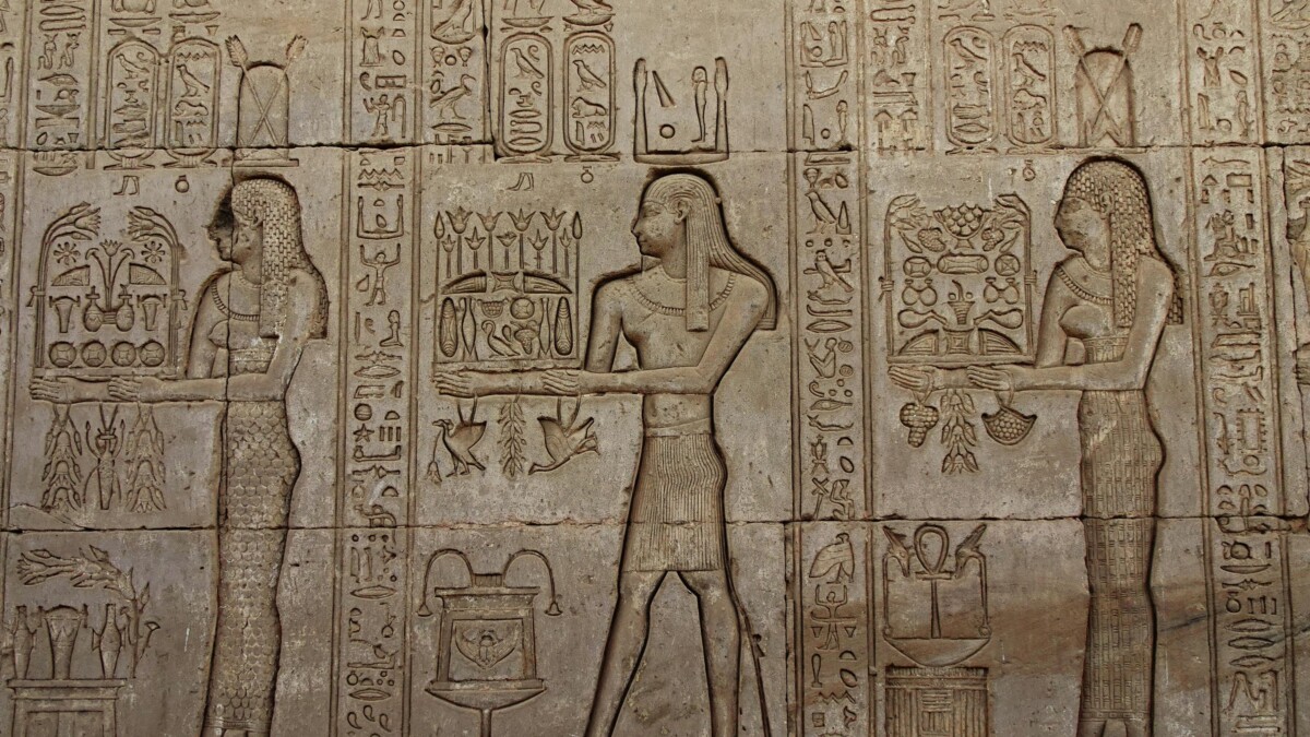 Close-up of detailed carvings on the walls of the Temple of Hathor, depicting ancient Egyptian figures presenting offerings