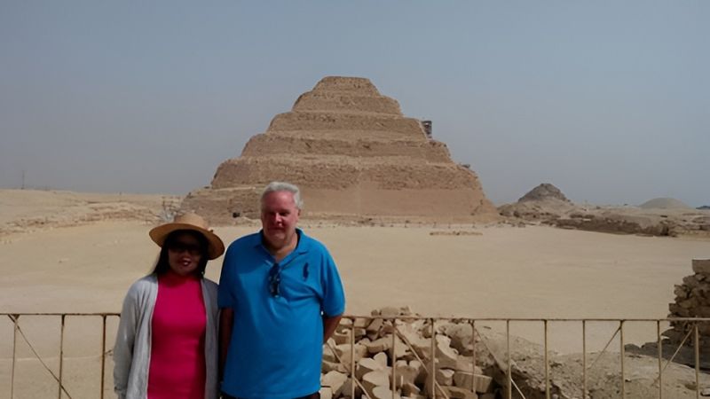 A panoramic view of the Step Pyramid in Saqqara, Egypt, surrounded by desert sands and clear blue skies