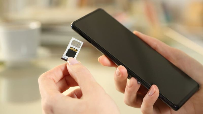 Close-up of hands inserting a SIM card into a smartphone