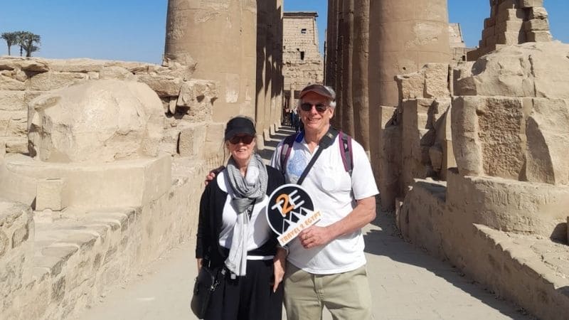 Visitors standing in front of the massive Great Pylon of Karnak Temple, surrounded by ancient stone carvings